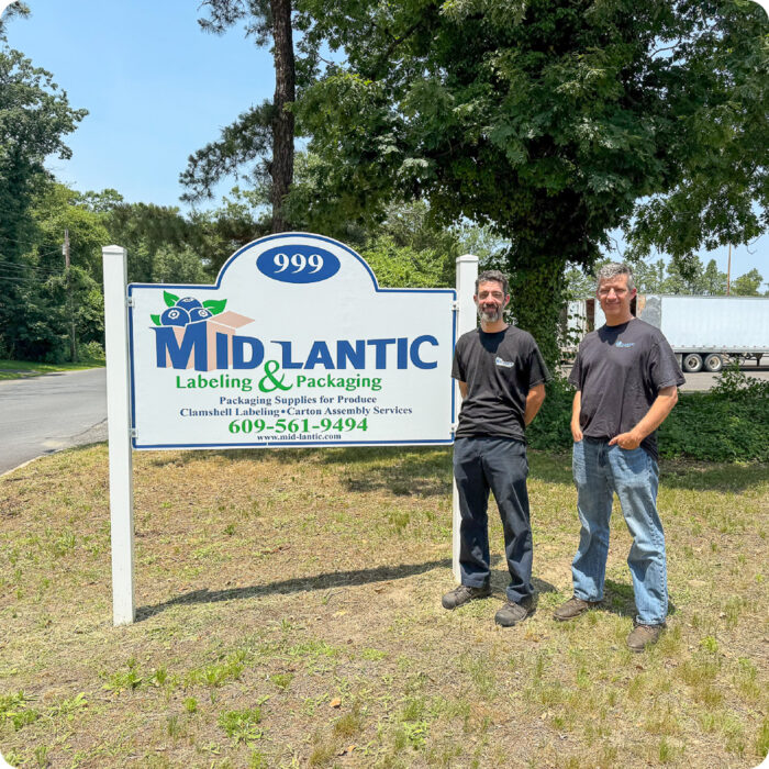 Owners of Mid-lantic Labeling and Packaging standing next to their sign.